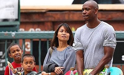 A picture of Dave Chappelle in public with his sons and wife.